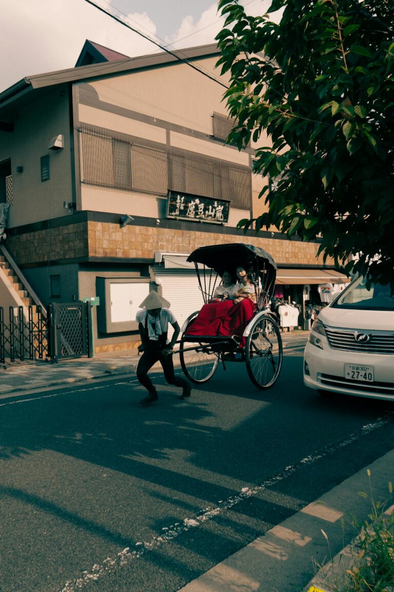 A man pulls a rickshaw with tourists on a vibrant street in Kyoto, Japan, showcasing cultural tradition.