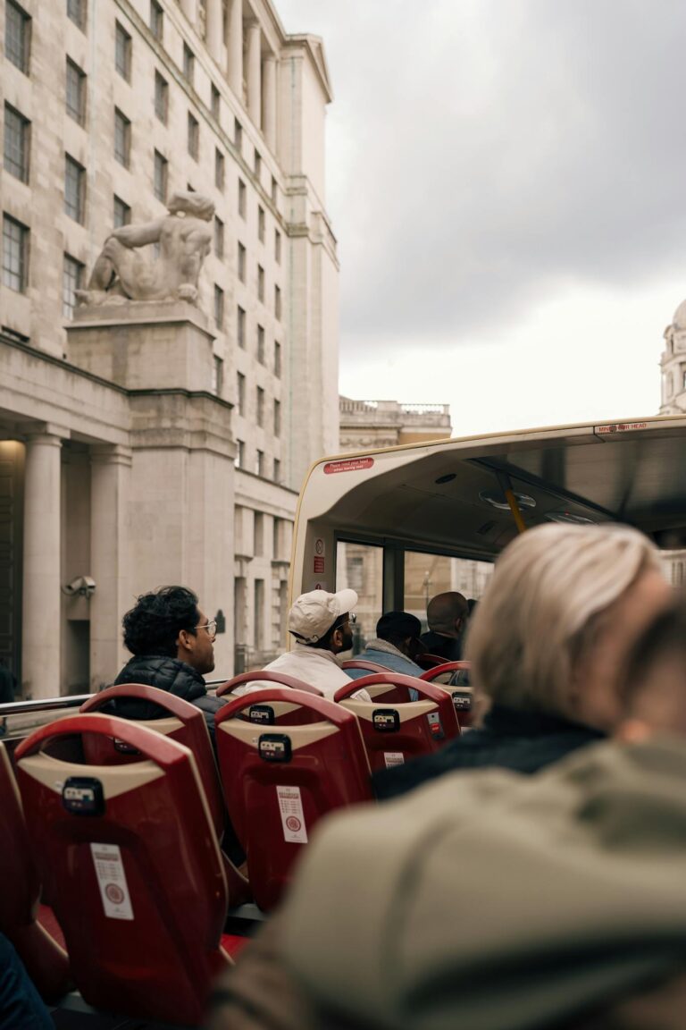 People enjoying a scenic tour on an open-top bus in a bustling city atmosphere.